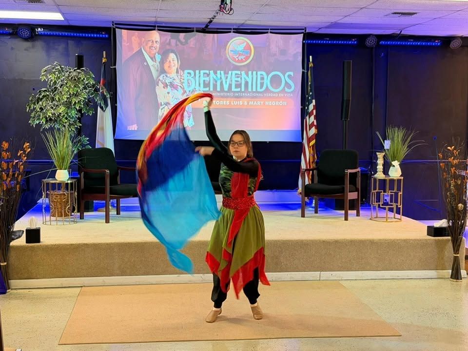 Performer dancing with flowing red and blue fabric on stage at formal event with welcome sign